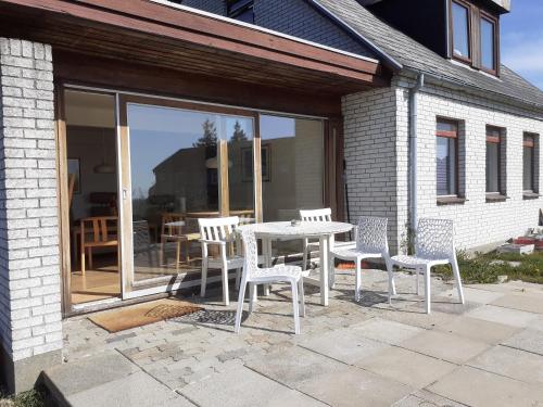 een tafel en stoelen op een patio met een tafel en ramen bij Svendborg Cosy in Svendborg