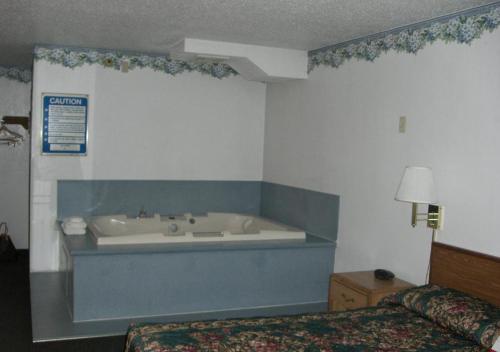 Habitación con bañera en un dormitorio. en Norwood Inn and Suites - Minneapolis-St Paul Roseville, en Roseville