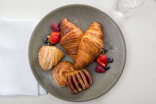 a gray plate with croissants and fruit on it at Novotel Newcastle Beach in Newcastle