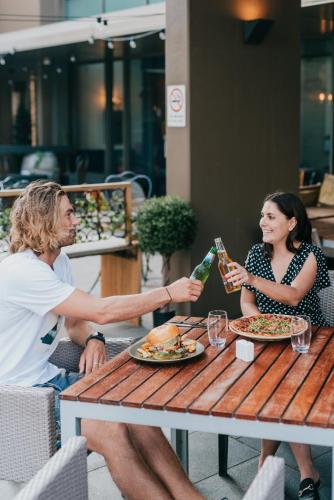 a man and woman sitting at a table drinking wine at Novotel Newcastle Beach in Newcastle