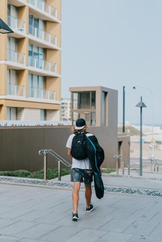 a man walking down a sidewalk with a backpack at Novotel Newcastle Beach in Newcastle