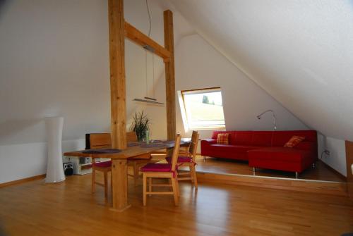 sala de estar con mesa y sofá rojo en Drei Tannen und Ferienhaus Schneider en Todtnau