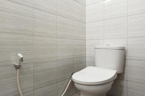 a bathroom with a toilet and a hose at RedDoorz near Taman Merdeka Metro Lampung in Lampung