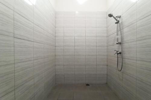 a bathroom with a shower with white tile at RedDoorz near Taman Merdeka Metro Lampung in Lampung