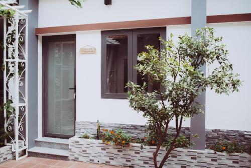 a white house with a window and a tree at ngaunhien's house - Homestay in Thôn Dư Khánh