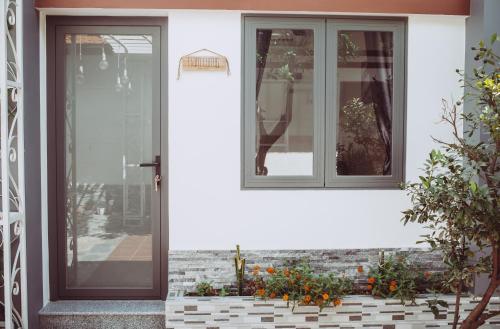 a front door of a white house with flowers at ngaunhien's house - Homestay in Thôn Dư Khánh
