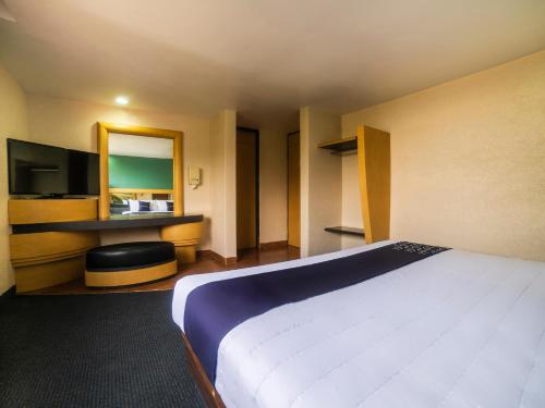 ein Hotelzimmer mit einem großen Bett und einem Spiegel in der Unterkunft Capital O Autoparador Del Valle,Centro Industrial Tlalnepantla in Mexiko-Stadt