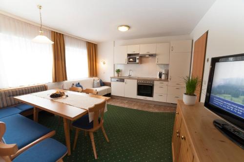 a living room with a dining table and a kitchen at Urlaubsland Sonnfeld in Flachau