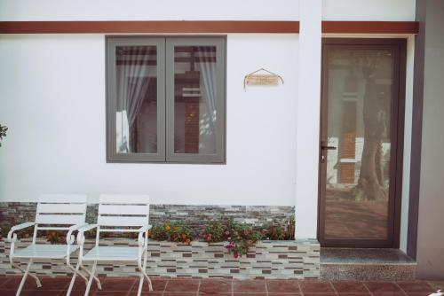 two chairs sitting on a porch next to a door at ngaunhien's house - Homestay in Thôn Dư Khánh