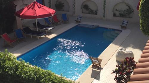 a swimming pool with chairs and an umbrella at Chez Nagy in Alexandria