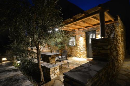 a stone house with a table and a tree at K Homes-Family Stone Suite in Tinos Town