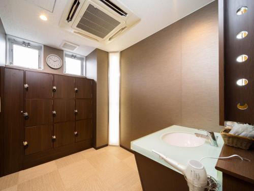 a bathroom with a sink and a clock on the ceiling at Super Hotel Nagaizumi Numazu Inter in Nagaizumi