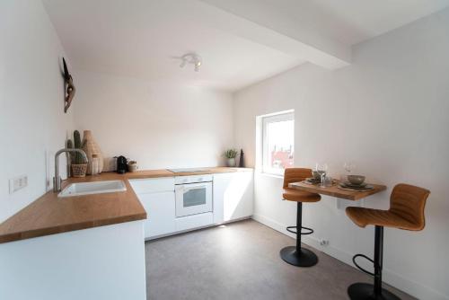 a kitchen with white cabinets and a table and chairs at Bamboa Beachhouse in Zandvoort