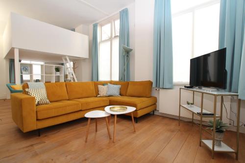 a living room with a yellow couch and a tv at Citystays Deventer in Deventer