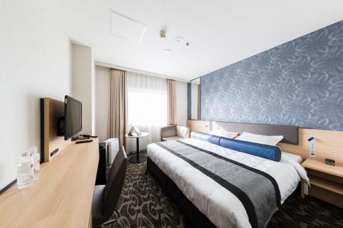 a hotel room with a bed and a television at Shin Osaka Esaka Tokyu REI Hotel in Suita