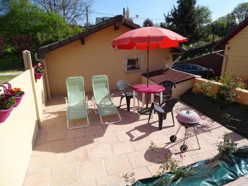 patio ze stołem, krzesłami i parasolem w obiekcie gite proche etretat w mieście Tourville-les-Ifs