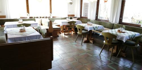 un comedor con mesas, sillas y ventanas en Sonneck Pension en Pfarrwerfen