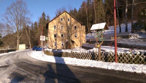 une maison sur le côté d'une route dans la neige dans l'établissement Pension Sommerfrische, à Ehrenfriedersdorf