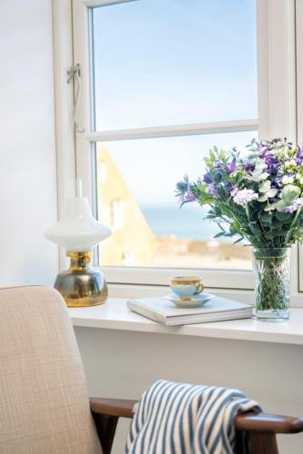 a window sill with a vase of flowers and a lamp at Grønbechs Hotel in Allinge