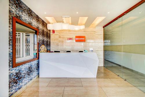 a lobby with a white counter and a glass wall at FabHotel Naman Palace in Bhopal
