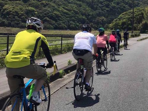 a group of people riding bikes down a road at YUKUSA OHSUMI UMI no GAKKO in Kanoya