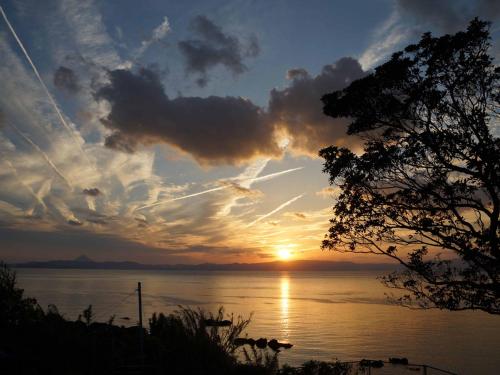 a sunset over a body of water with the sun setting at YUKUSA OHSUMI UMI no GAKKO in Kanoya