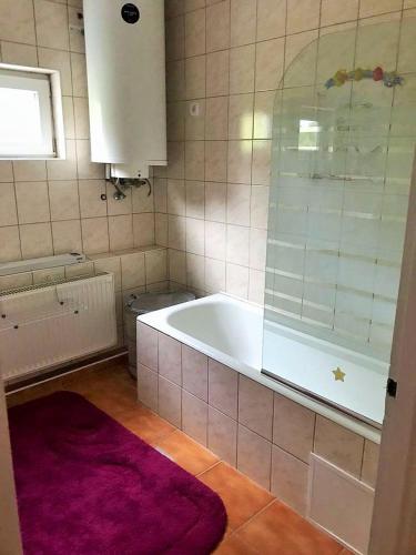 a bathroom with a tub and a purple rug at Kishableány Apartmanház in Badacsonytomaj