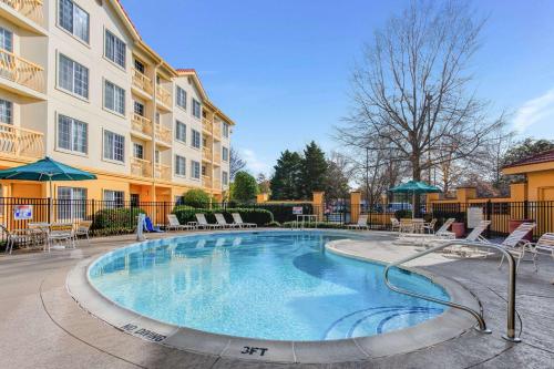 einen Pool mit Stühlen und ein Gebäude in der Unterkunft La Quinta by Wyndham Raleigh Durham Intl AP in Morrisville