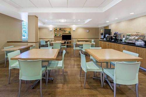 a restaurant with tables and chairs and a kitchen at La Quinta by Wyndham West Palm Beach Airport in West Palm Beach