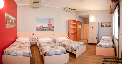 a room with three beds and a red wall at Central Hostel BG in Bergamo