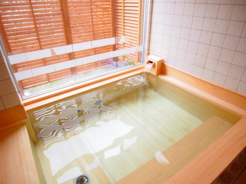 La salle de bains est pourvue d'une baignoire, d'une fenêtre et d'un lavabo. dans l'établissement Hotel Nikko-Kinugawa Inn Miyasaki, à Nikkō