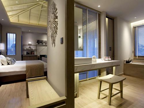 a hotel room with a large bed and a large window at Pullman Phuket Arcadia Naithon Beach - SHA Extra Plus in Nai Thon Beach