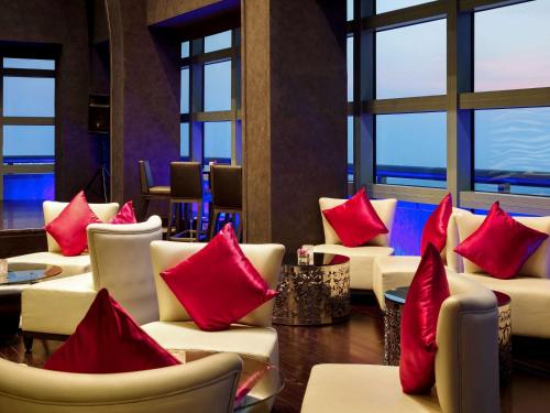 a room with white chairs with red pillows at Sofitel Abu Dhabi Corniche in Abu Dhabi