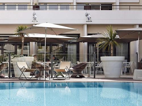 a patio area with chairs, a table, and a pool at Novotel Avignon Centre in Avignon