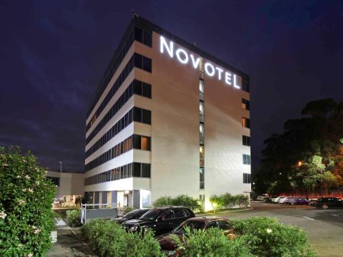 un hotel de novación con coches aparcados en un aparcamiento en Novotel Sydney West HQ, en Rooty Hill