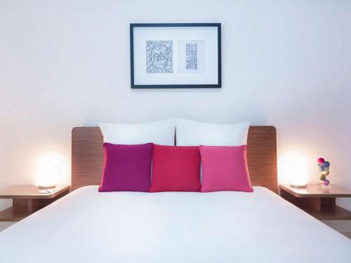 a bedroom with a white bed with two pink pillows at Adagio Abu Dhabi Al Bustan in Abu Dhabi