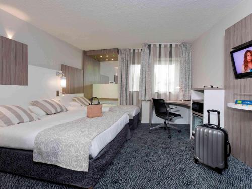 um quarto de hotel com duas camas e uma secretária em ibis Styles Melun em Rubelles