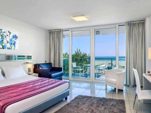 1 dormitorio con cama y vistas al océano en Mercure Hotel Rimini Artis, en Rímini