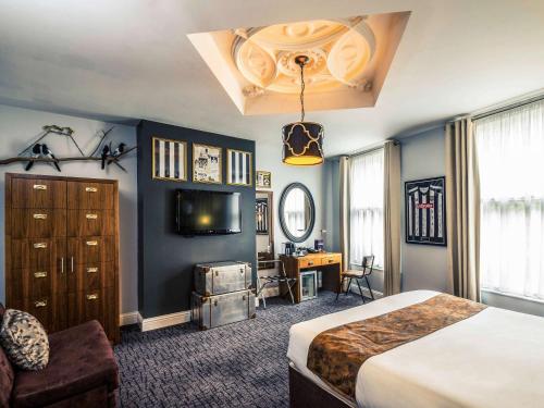 a bedroom with a bed and a desk and a television at Mercure Nottingham City Centre Hotel in Nottingham