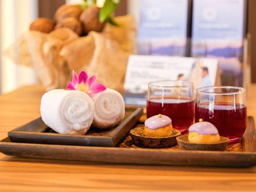 a tray with towels and two glasses of tea at Grand Mercure Phuket Patong in Patong Beach