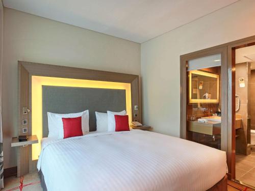 a bedroom with a large white bed with red pillows at Novotel Ahmedabad in Ahmedabad