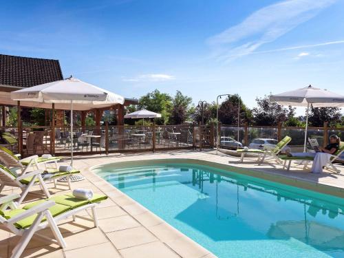 a swimming pool with lawn chairs and umbrellas at ibis Styles Périgueux Trélissac in Trélissac