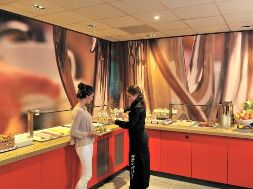 
a woman standing in front of a counter in a restaurant at ibis Rotterdam City Centre in Rotterdam
