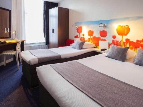 a hotel room with two beds and a desk at ibis Styles Amsterdam City in Amsterdam