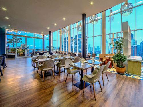 a restaurant with tables and chairs and large windows at All Seasons Jakarta Thamrin in Jakarta