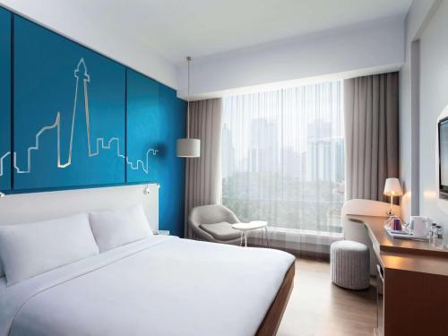 a hotel room with a bed and a blue wall at All Seasons Jakarta Thamrin in Jakarta