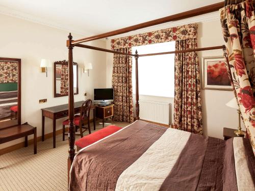 a hotel room with a bed and a desk at Mercure York Fairfield Manor Hotel in York