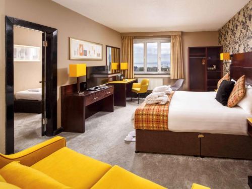 een hotelkamer met een groot bed en een bureau bij Mercure Ayr Hotel in Ayr