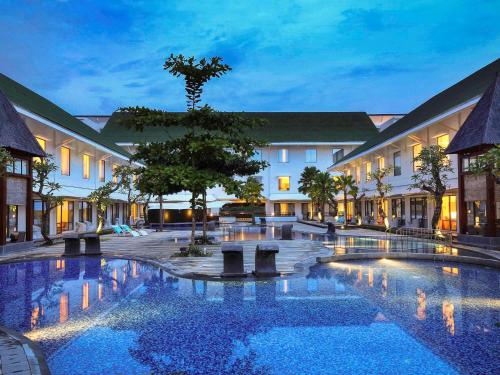 a hotel courtyard with a large pool at night at Novotel Banjarmasin Airport in Banjarbaru