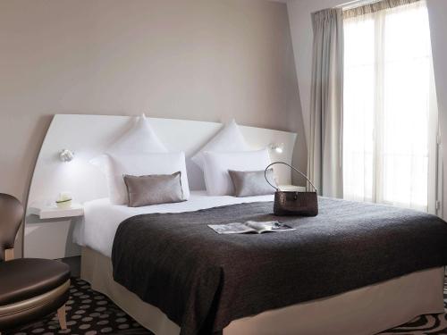 - une chambre avec un grand lit et une chaise dans l'établissement Mercure Paris Levallois, à Levallois-Perret